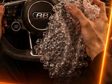 Hands crushing bubble wrap wrapped around an Audi R8 steering wheel